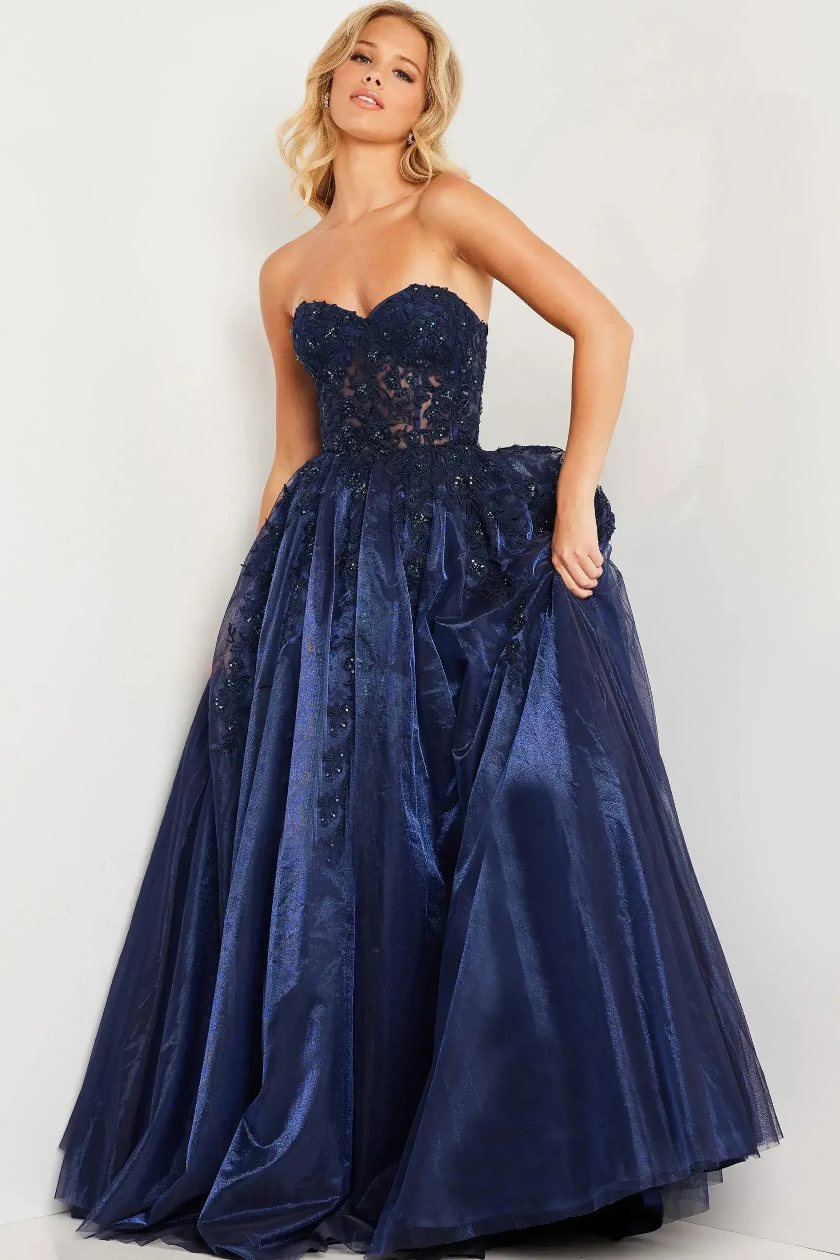 A woman in an elegant navy blue strapless ball gown with intricate lace detailing and a full skirt.