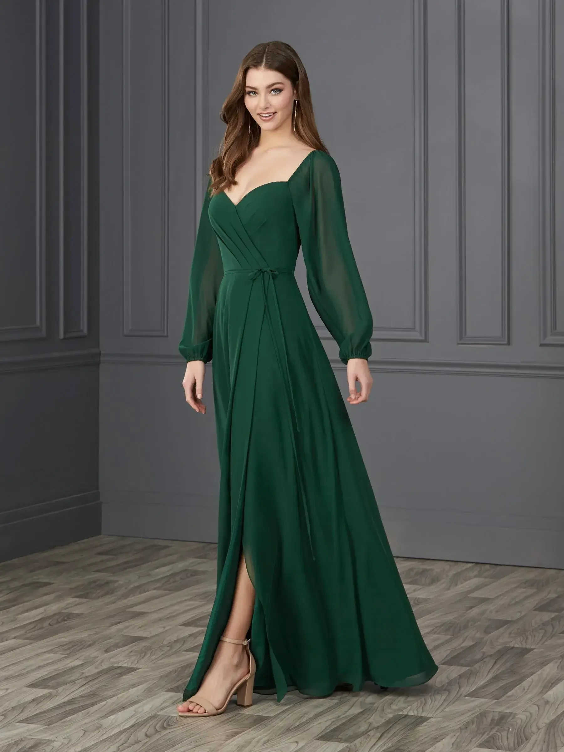Model is wearing a long sleeve chiffon bridesmaid dress with a thigh high slit