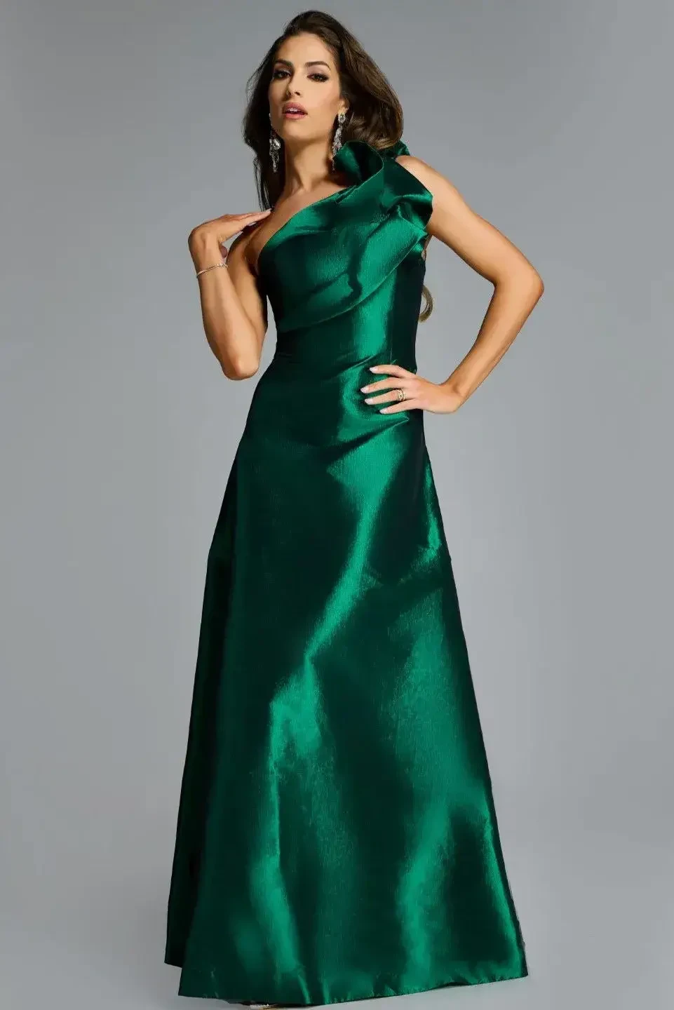 A model wearing a one-shoulder, long green satin gown with a bold design and elegant pose.
