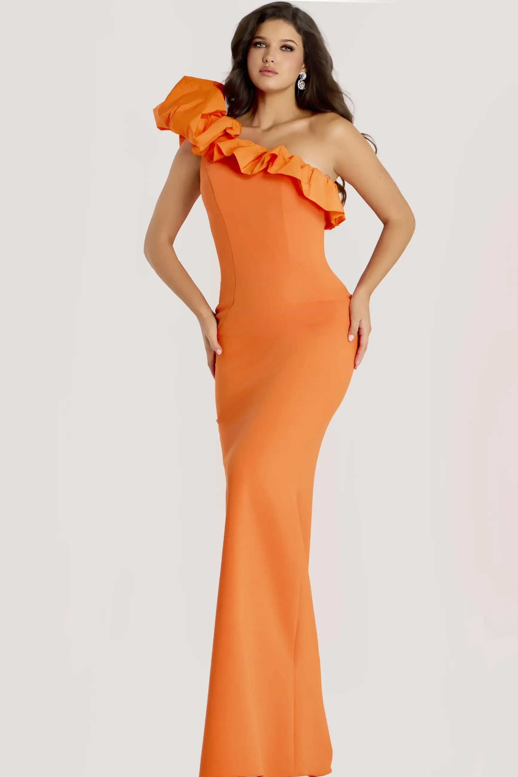 A model poses in an elegant, form-fitting orange dress with a ruffled shoulder detail.
