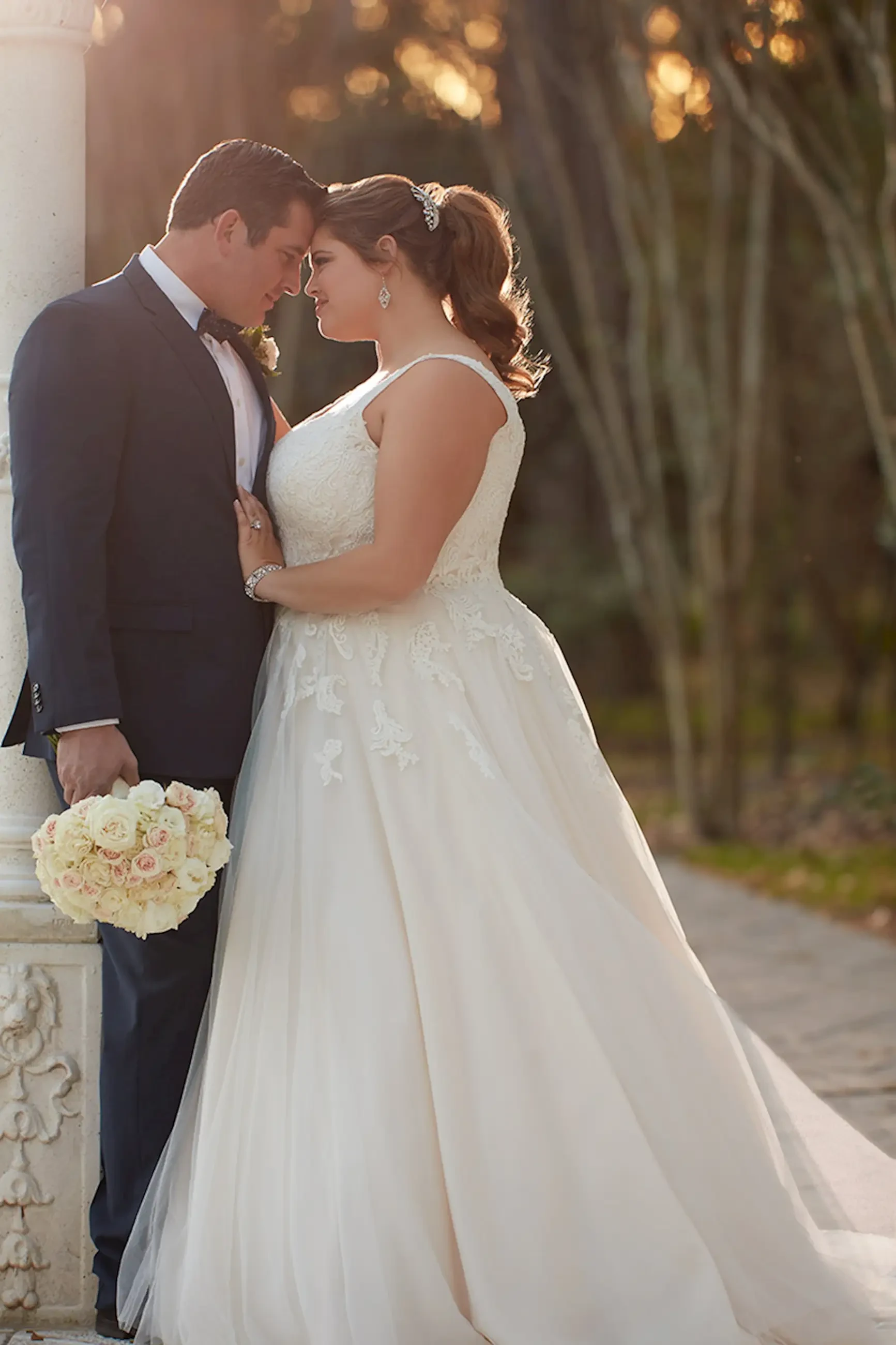Model is wearing an a-line plus size wedding dress with a tulle skirt and v back