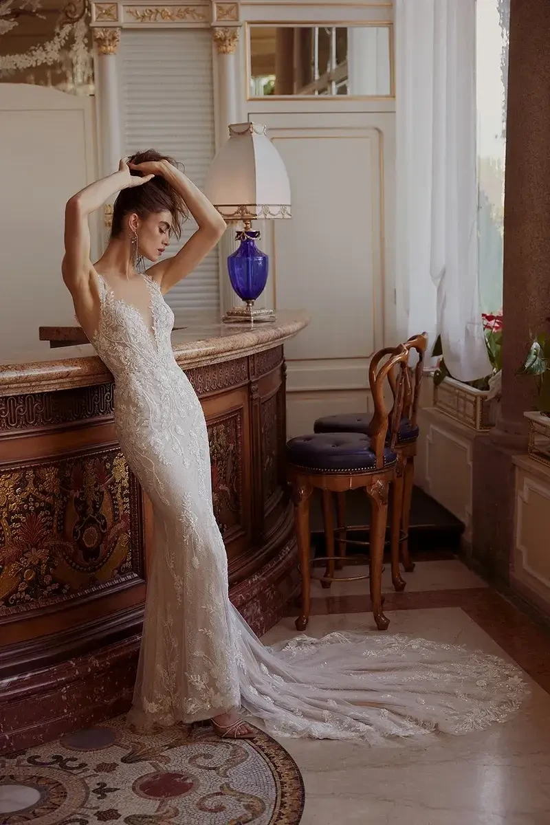 model is wearing a sleeveless lace fitted bridal gown with an open back