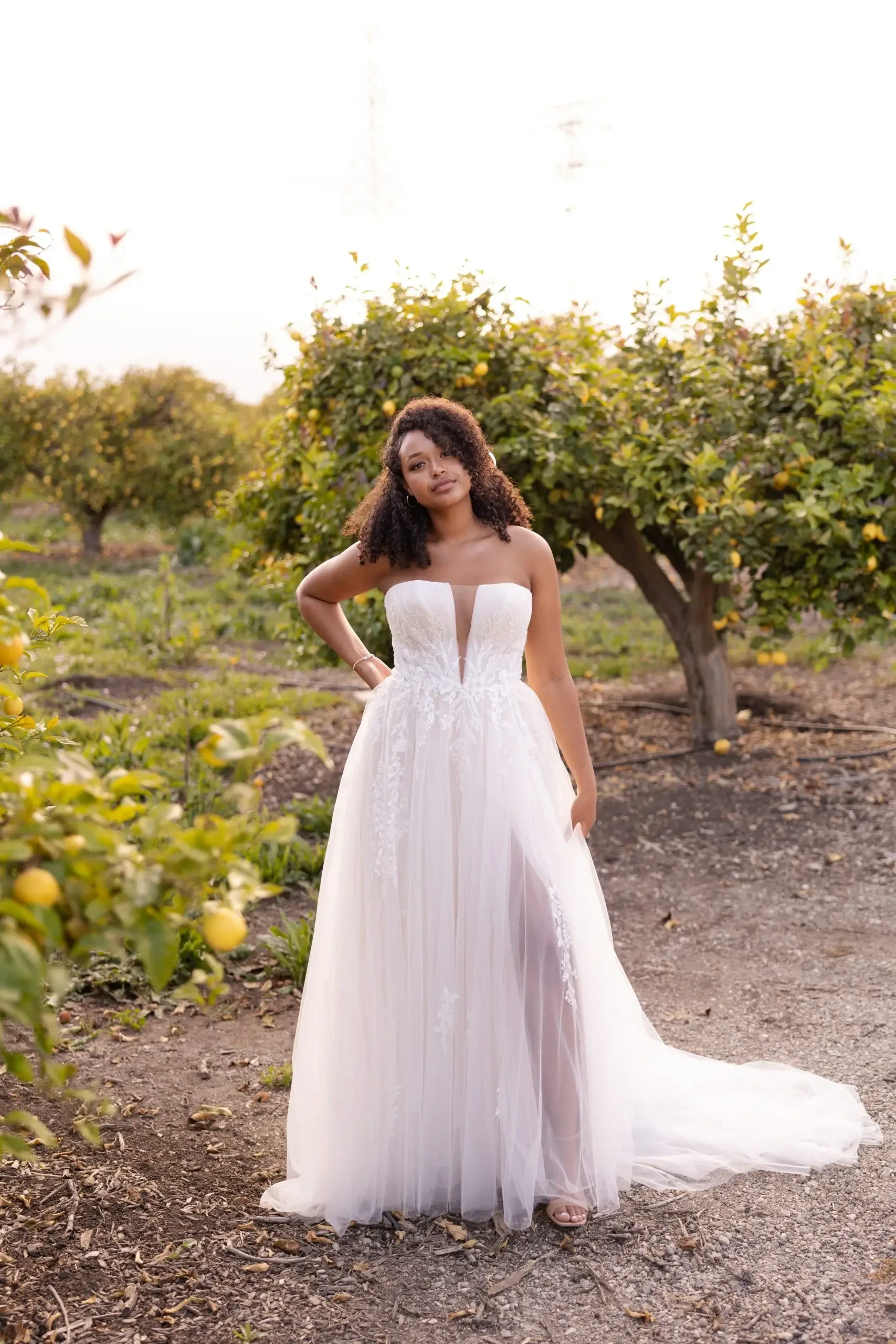 Model is wearing a strapless plus size wedding dress with a tulle a-line skirt