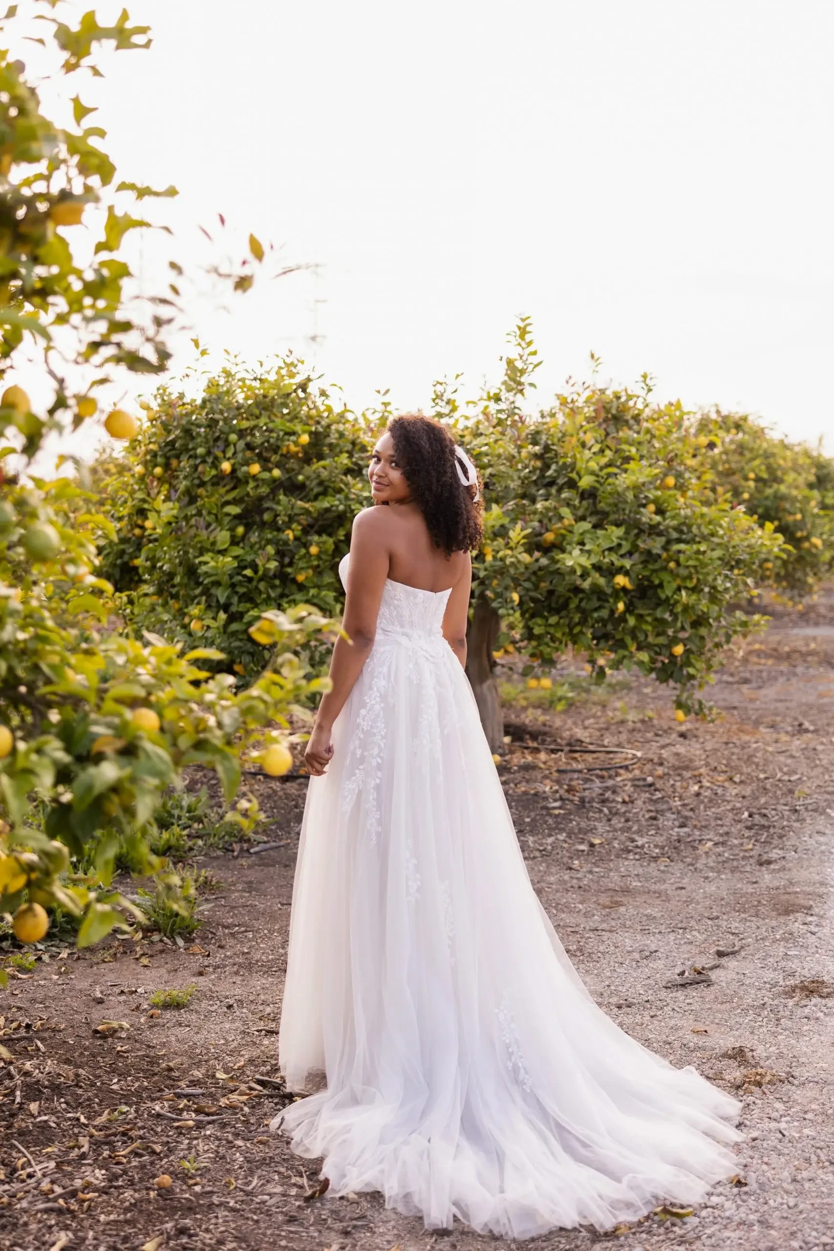 Model is wearing a strapless plus size wedding dress with a tulle a-line skirt